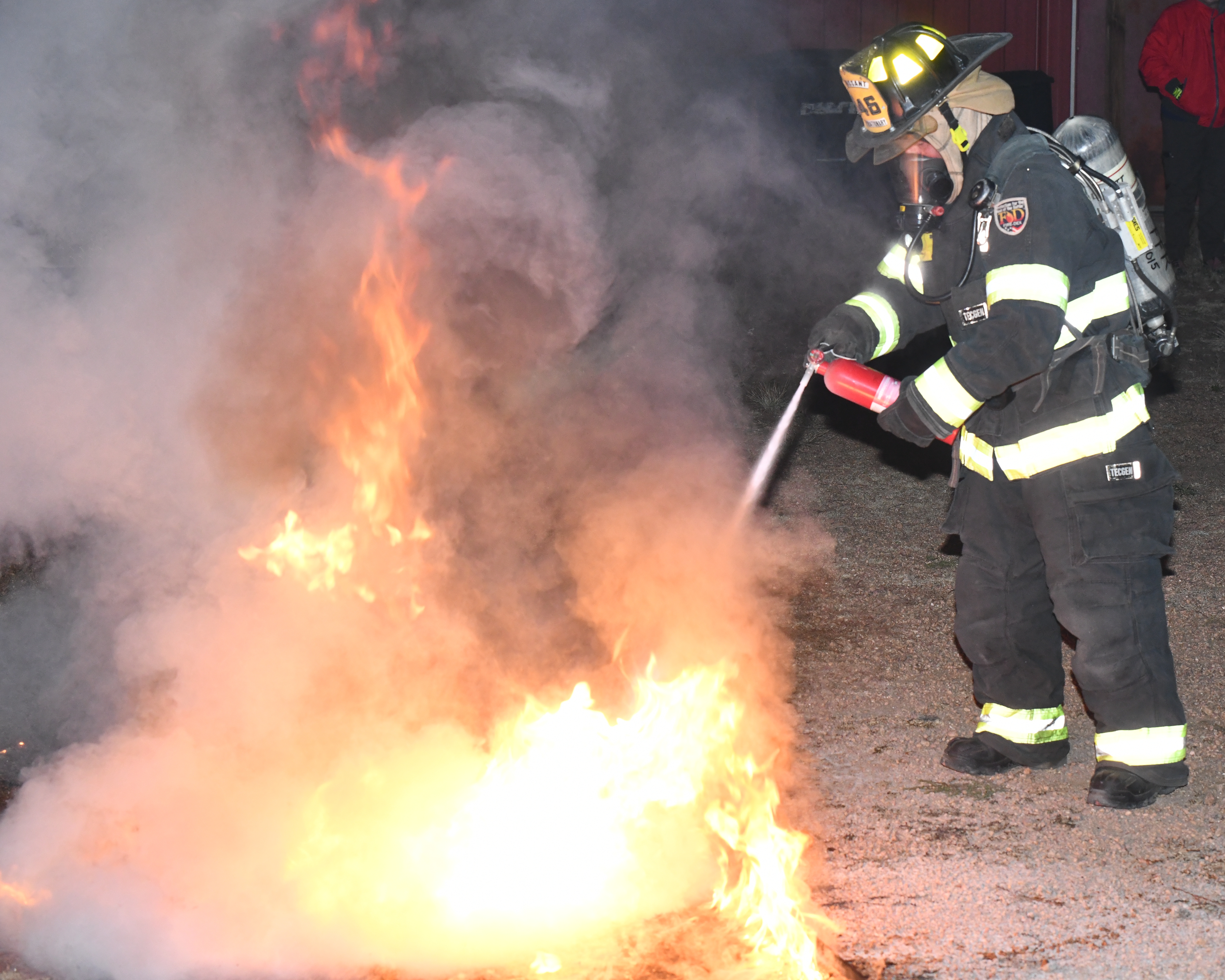 Fire fighter putting out a fire with a fire extinguisher during a training exercise